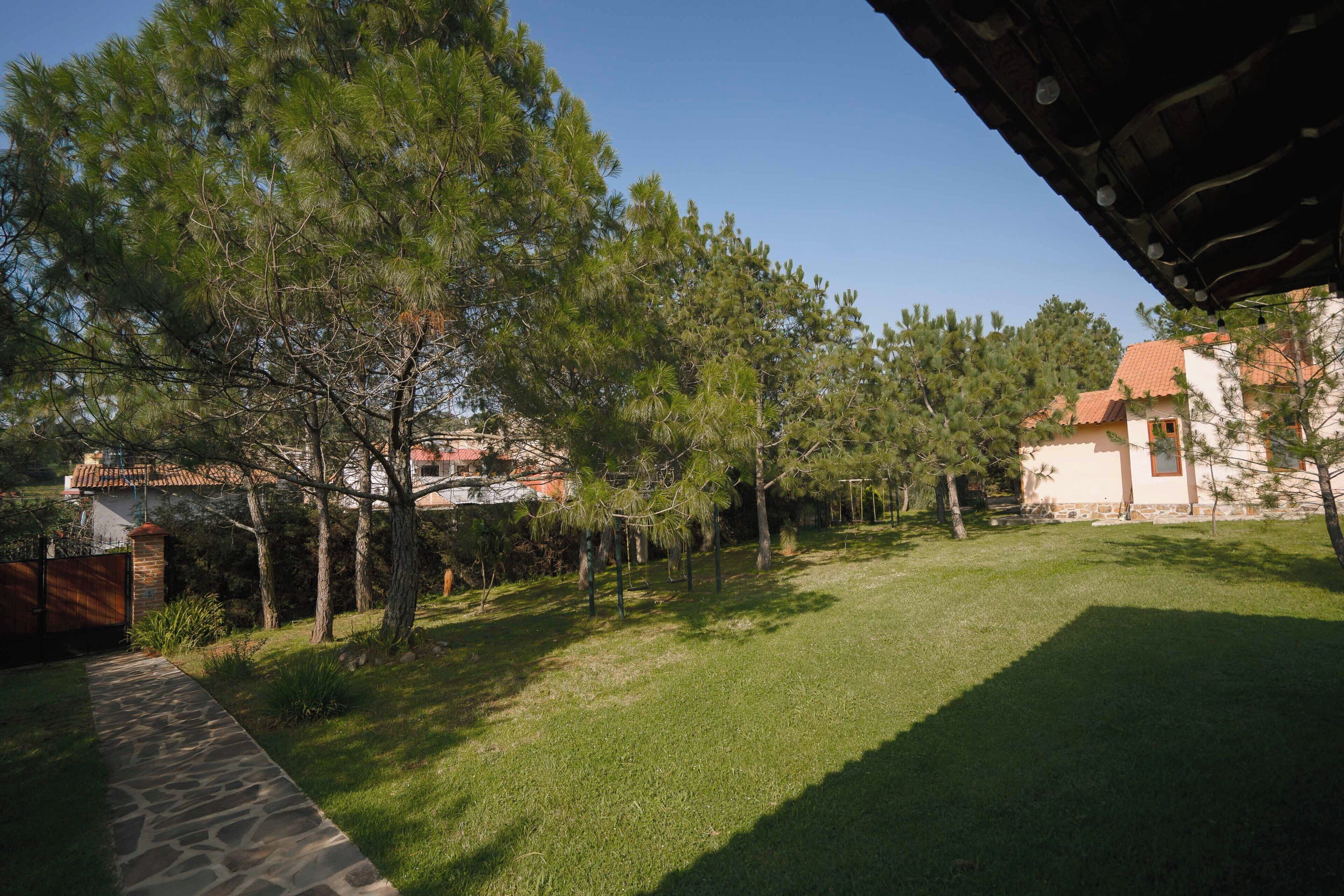 A well-maintained grassy area with trees and a stone pathway leading to a building with a tiled roof.
