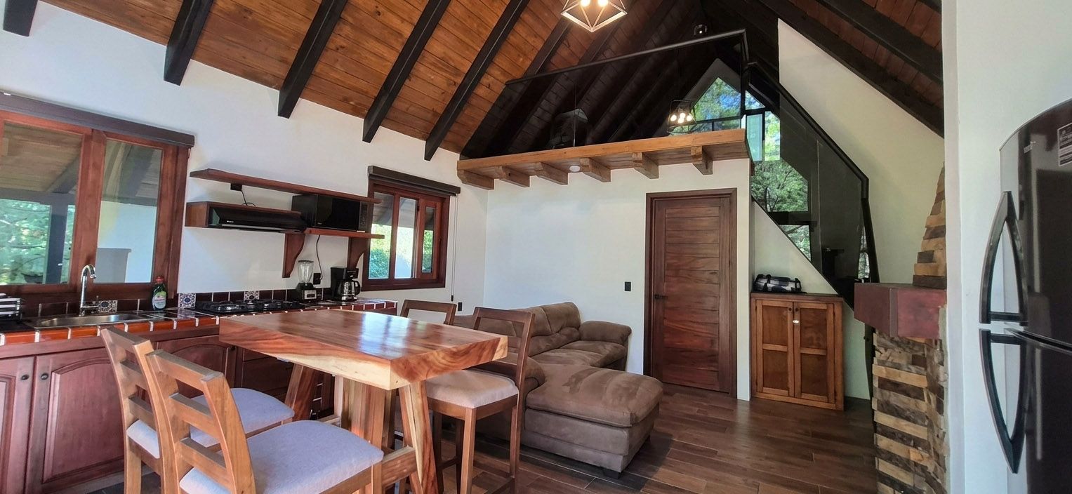A modern kitchen with a wooden table and chairs, a built-in oven, and a refrigerator.
