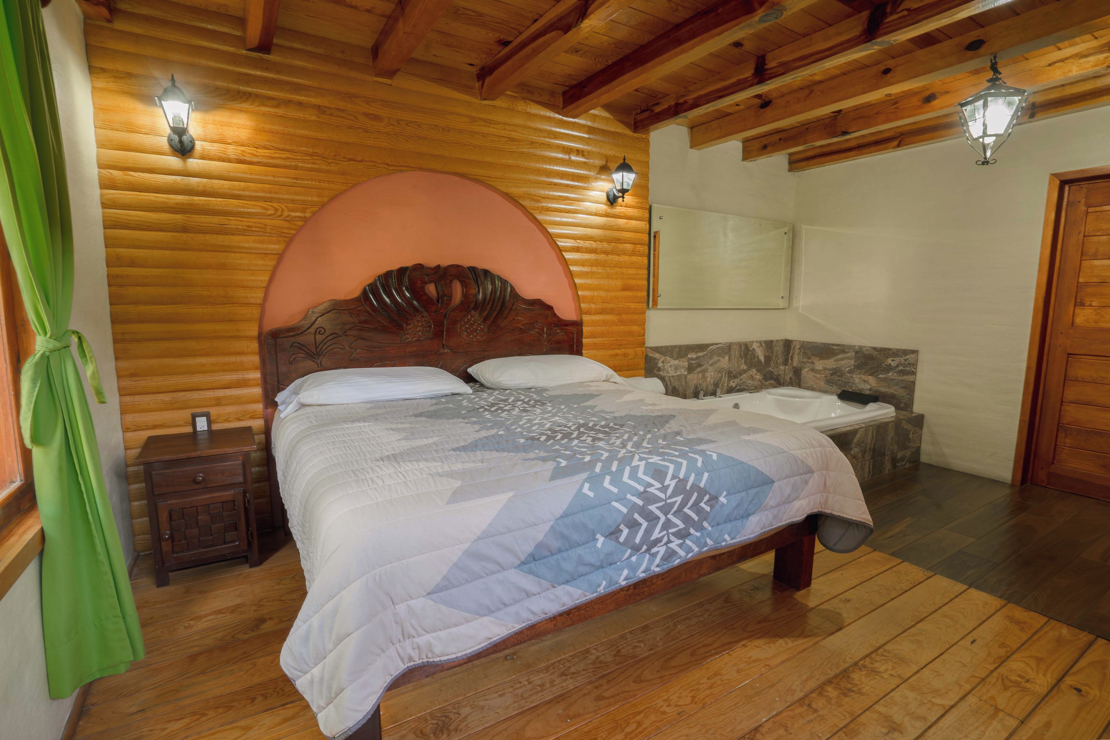 Un dormitorio con paneles de madera, una cama, una mesita de noche, una cortina verde y una pared de piedra.