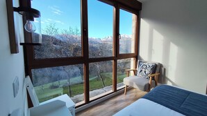 A bedroom with large windows, a bed, a chair, and a desk. - Apartment with views to the Picos de Europa 4 pax - 1 (Tollo)