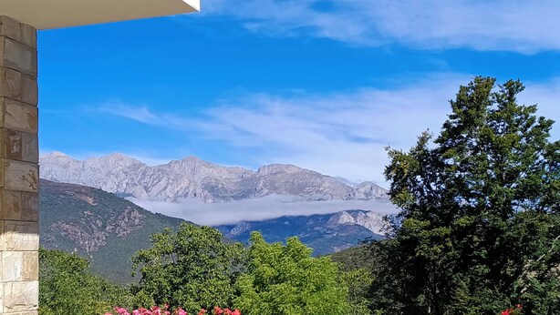 A terrace with terracotta planters of pink flowers, a wooden fence, and a mountain view. - Apartment with views to the Picos de Europa 4 pax - 1 (Tollo)