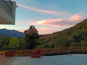 Aussicht auf eine gebirgige Landschaft mit Holzzaun und Blumentöpfen.