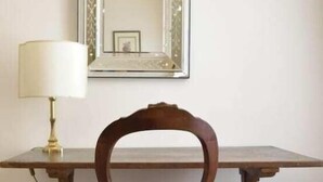 Una mesa de comedor con una silla, una lámpara y un espejo en la pared.