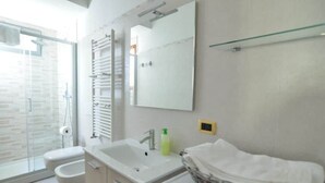 Un baño moderno con cabina de ducha de vidrio, un lavabo blanco y un espejo grande.
