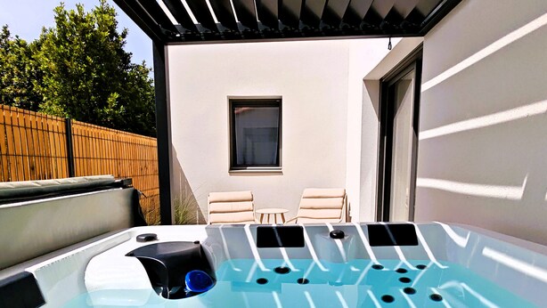 Una vasca idromassaggio con pannello di controllo, due poltrone relax e una finestra in un ambiente esterno.