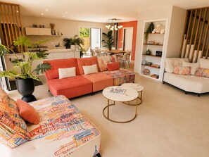 Ein modernes Wohnzimmer mit einem Ecksofa, einem Couchtisch und einem Essbereich mit Stühlen.