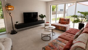 Un soggiorno moderno con un divano, una TV, una lampada da terra e un tavolino.