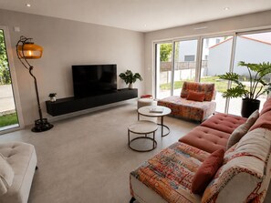 Ein modernes Wohnzimmer mit einer Couch, einem Fernseher, einer Stehlampe und einem kleinen Tisch.