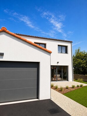 Ein modernes, zweistöckiges Haus mit Garage, großen Fenstern und einem gepflegten Rasen.