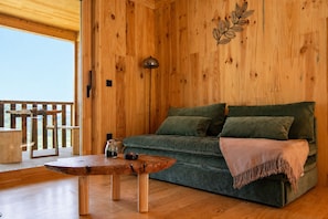A wooden interior with a sofa, a table, and a lamp.