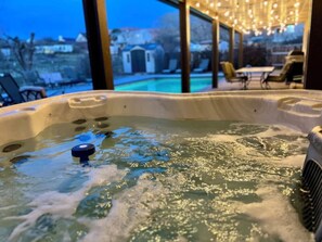 Ein Whirlpool mit Blick auf einen Pool und eine Außenlounge.