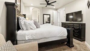 Ein Schlafzimmer mit Bett, Kommode, Fernseher und Deckenventilator.