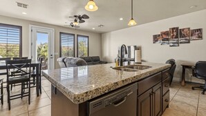 Eine moderne Küche mit Granit Arbeitsplatten, einem integrierten Geschirrspüler und einem Essbereich mit einer Couch und Stühlen.
