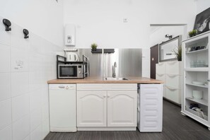 Eine kompakte Küche mit Geschirrspüler, Mikrowelle und einem Edelstahlkühlschrank.