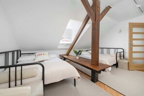 Ein Schlafsaalzimmer mit Etagenbetten, einem Holztisch, einer kleinen Pflanze und einem Dachfenster.