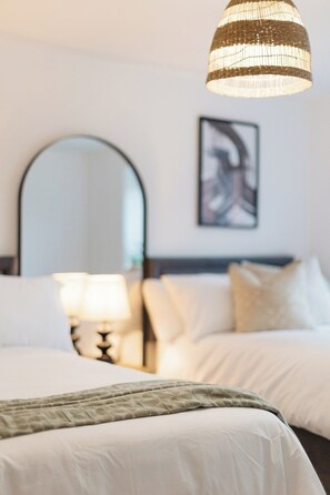 Een hotelkamer met een bed, een bedlamp, een spiegel en een kunstwerk aan de muur.