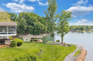 Une propriété située au bord d’un lac, comprenant une grande maison, un chalet plus petit et une pelouse bien entretenue.