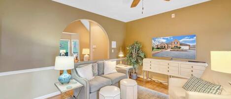 A living room with a ceiling fan, a sofa, a coffee table, a side table, and a lamp.