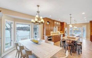 Une cuisine spacieuse dotée d’un grand îlot central, de meubles en bois et offrant une vue sur un lac.