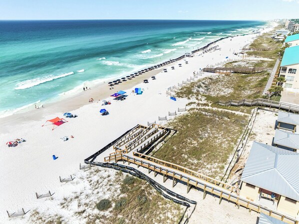 Een strand met een houten vogelzangpad, strandparasols en een zandstrand.