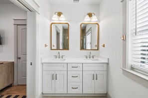A bathroom with white cabinetry, two sinks, and a mirror with a gold frame. - Sunfish Royale | Private Beach, Billiards, Spa, Pickleball (Destin)