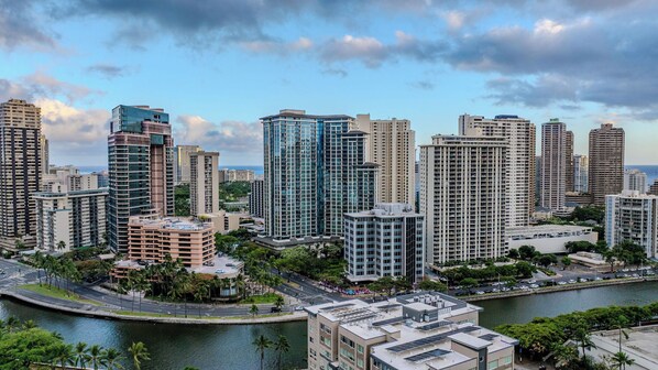A cityscape with high-rise buildings, a waterfront, and a road with vehicles. - Kalākaua Breeze by Avantstay Designer Condo w/ Pool + Spa + Gym Access Walk to Ala Moana + Waikiki (Honolulu)