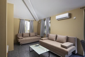 Ein Wohnzimmer mit zwei Sofas, einem Couchtisch und einer Wand-Klimaanlage.