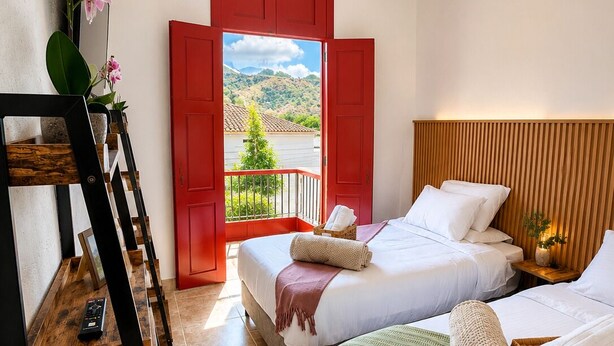 Un dormitorio con dos camas, una escalera de madera, una puerta roja y vistas al exterior.