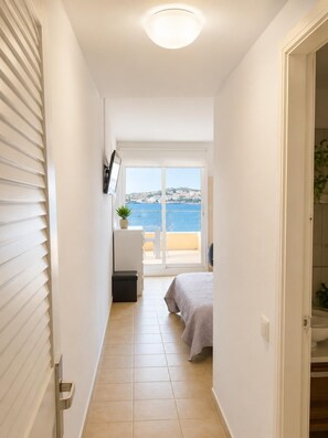 A narrow hallway leading to a balcony with a sea view, a bed, and a small table with a plant. - Sea View Apartment - Swimming pool and tennis (L'Escala)