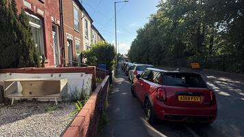 A residential street with houses, parked cars, and a clear sky.