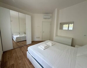 Ein Schlafzimmer mit einem Bett, einem Kleiderschrank, einem Spiegel und einer Klimaanlage.