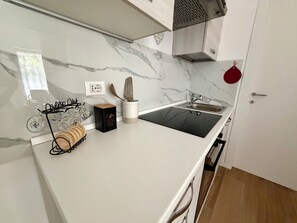 Eine Küche mit Marmorfliesenspiegel, einer Kaffeestation und einem Edelstahl-Spülbecken.
