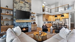 A modern living room with a stone fireplace, a flat-screen TV, and a cozy seating area.