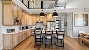 A modern kitchen with wooden cabinets, a stainless steel refrigerator, and a dining area with three chairs.