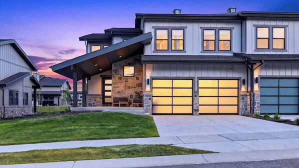 A modern two-story house with a stone facade, large garage doors, and a covered entryway.