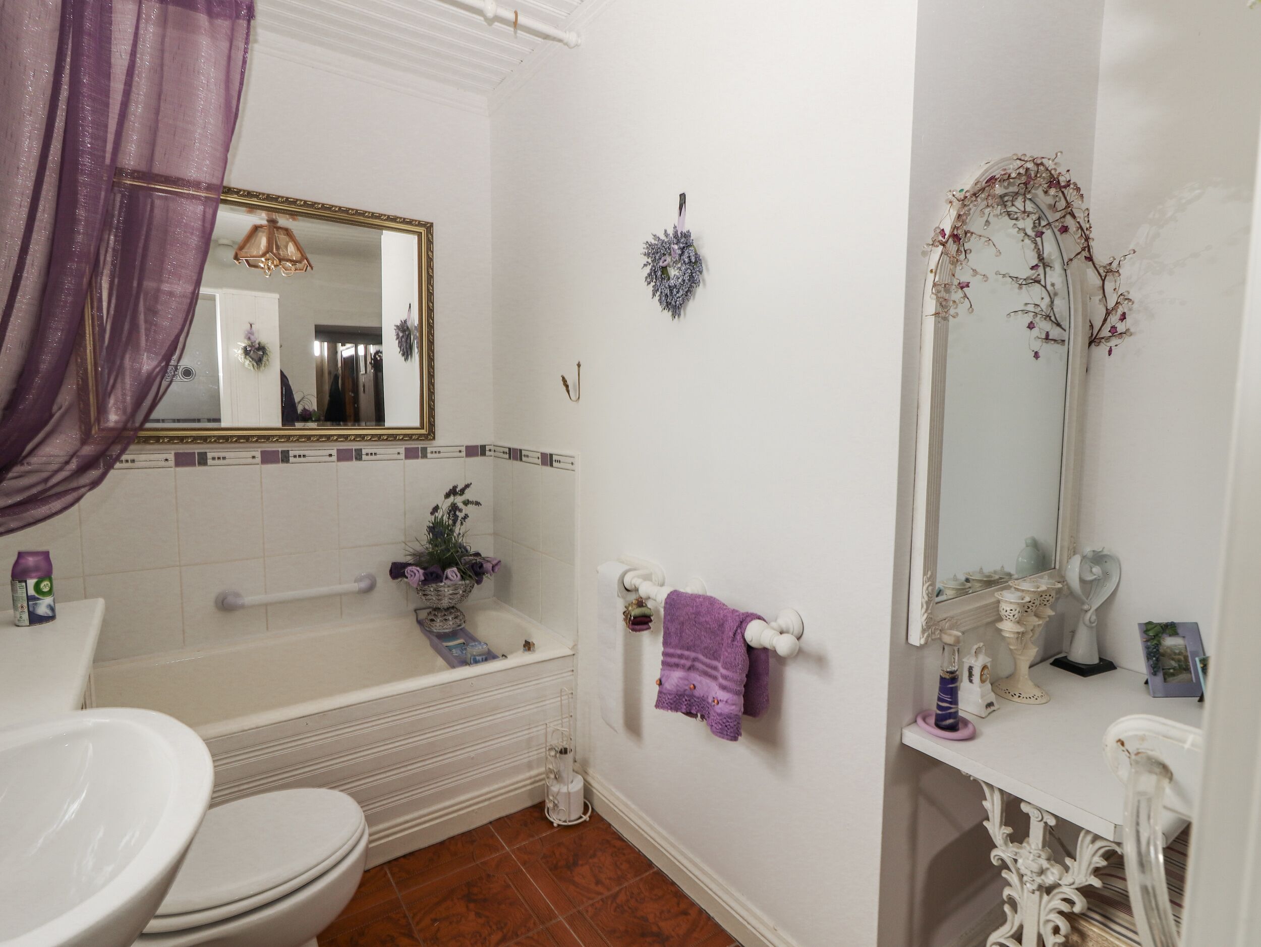 A bathroom with a toilet, bathtub, and a mirror.