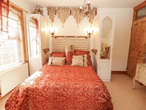 Ein Schlafzimmer mit einem großen Bett, einer Lüster, einem Spiegel und einem Holzschrank.
