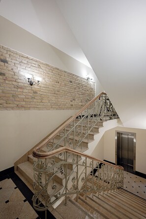 Eine Treppe mit aufwendigen Metallgeländern und einer Holzhandläufe, die zu einem Aufzug führt.