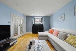A living room with a TV, sofa, and a window with curtains.