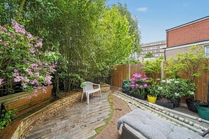 A garden with a wooden bench, potted plants, and a brick pathway.