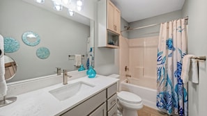 Ein Badezimmer mit Waschbecken, Spiegel, Toilette und Dusche.