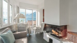 Un salon moderne doté d’une cheminée, de grandes fenêtres et offrant une vue sur les montagnes.