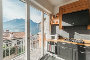 A kitchen with a view of mountains, a balcony, and a stove.