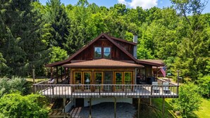 Eine Holzhütte mit einer Terrasse, umgeben von dichtem Wald.