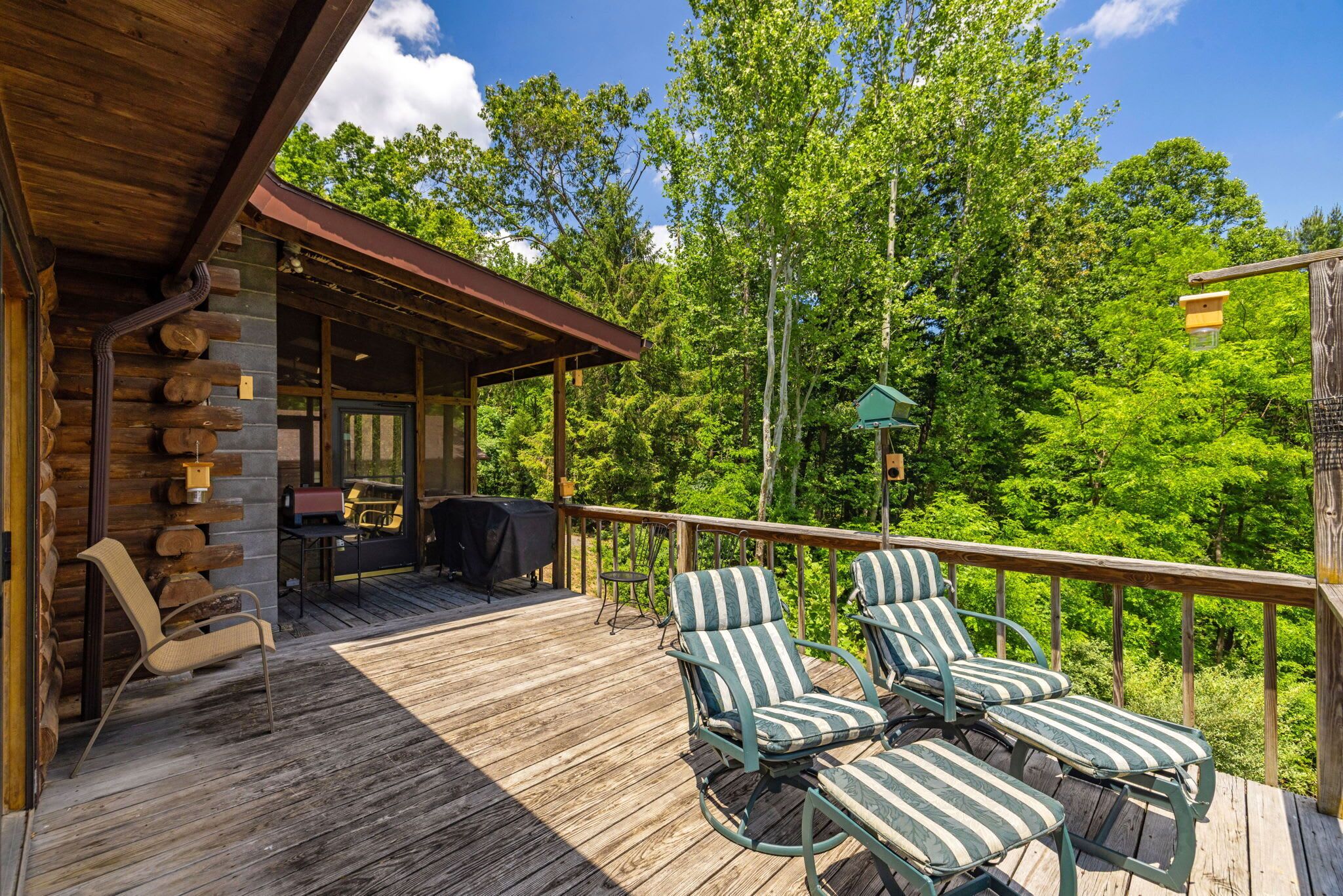 A wooden deck with lounge chairs, a barbecue grill, and a covered area with a table and chairs.