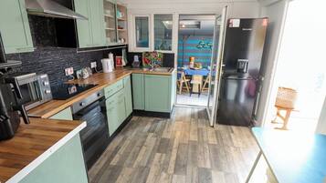 A modern kitchen with a wood floor, green cabinets, and a dining area with a table and chairs.