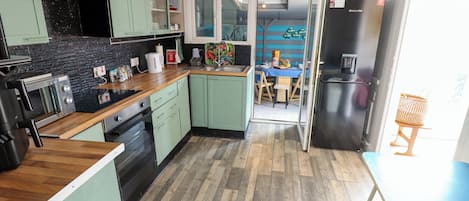 A modern kitchen with a wood floor, green cabinets, and a dining area with a table and chairs.