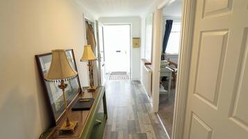 A hallway with a green console table, two lamps, and a door leading to another room.