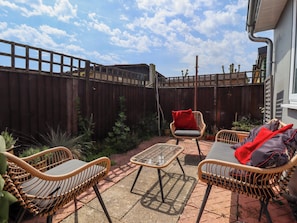 A patio with wicker furniture, a wooden fence, and potted plants. - Four Seasons (Grimsby)