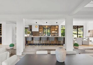 Eine moderne Küche mit Barhocker, einem großen Fenster und einem Essbereich mit einer Vase.